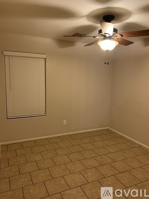 A room with a ceiling fan and a window with blinds.