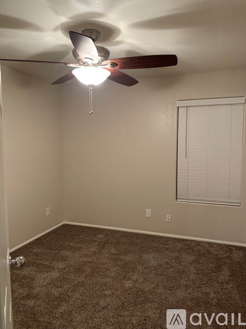 A room with a ceiling fan and carpeted floor.