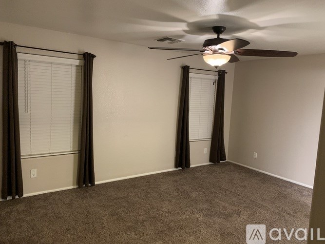 A room with a ceiling fan and carpeted floor.
