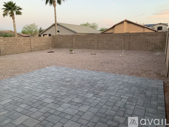 A backyard with a paved patio and a wall.