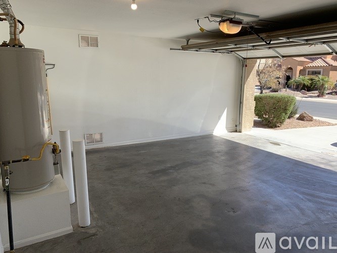 A large, empty room with a white wall and a concrete floor.