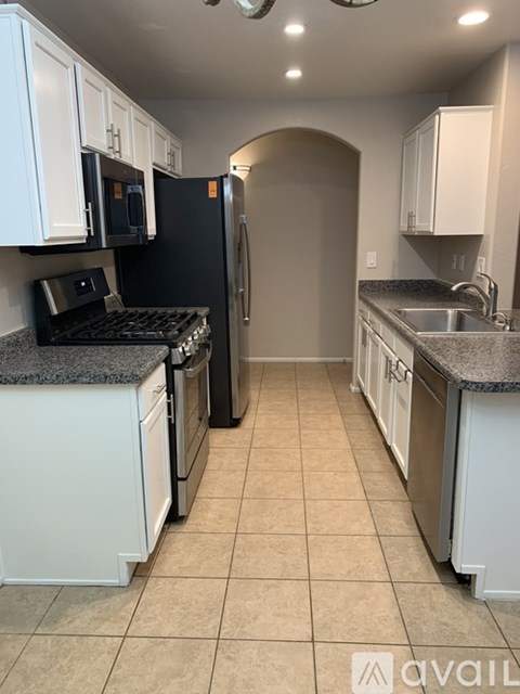 A kitchen with white cabinets and a black fridge.