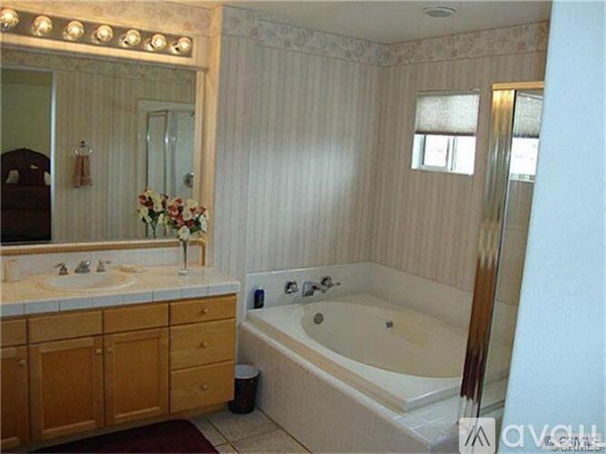 A bathroom with a tub, sink, and mirror.