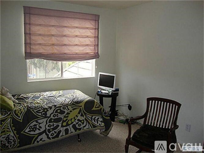 A bedroom with a bed, a chair, and a computer desk.