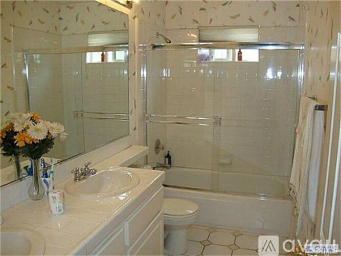 A white bathroom with a flower vase on the sink.