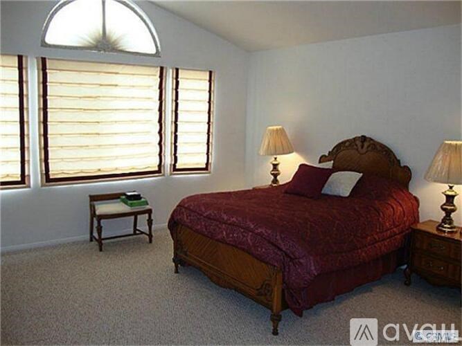 A bedroom with a red bed and two lamps.
