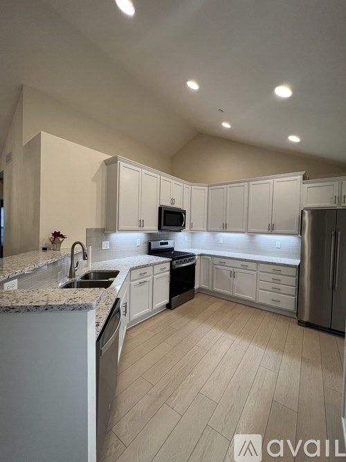 A kitchen with white cabinets and a granite countertop.