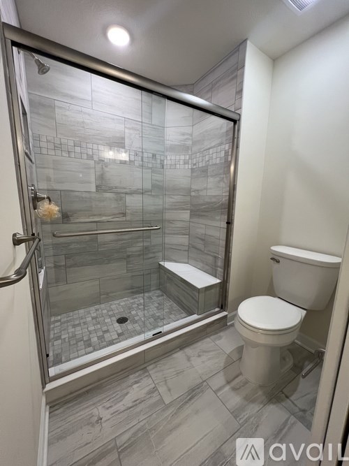 A bathroom with a glass shower door and a toilet.