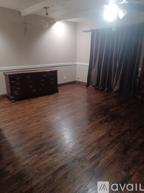 A room with a wooden floor and a black dresser.