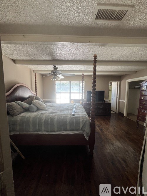 A bedroom with a bed, dresser, and window.