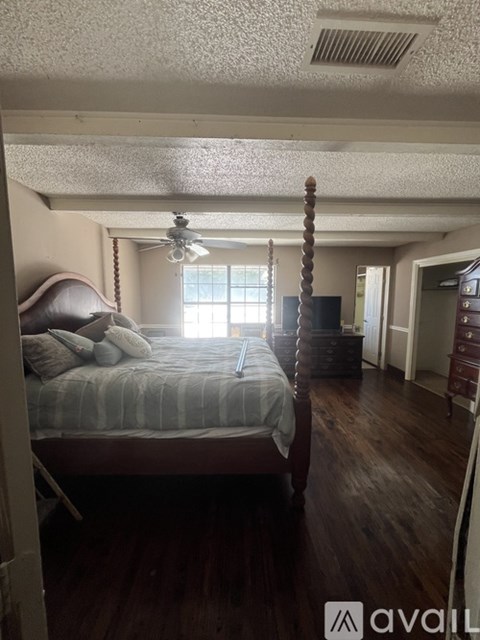 A bedroom with a bed, dresser, and window.