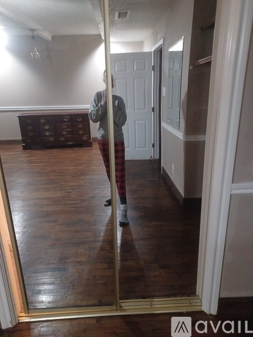 A person standing in a room with a wooden floor.