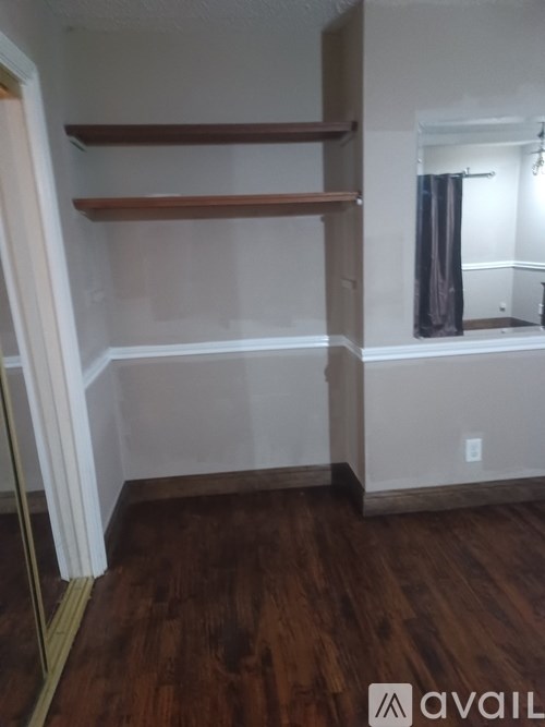 A room with wooden floors and a window with a curtain.