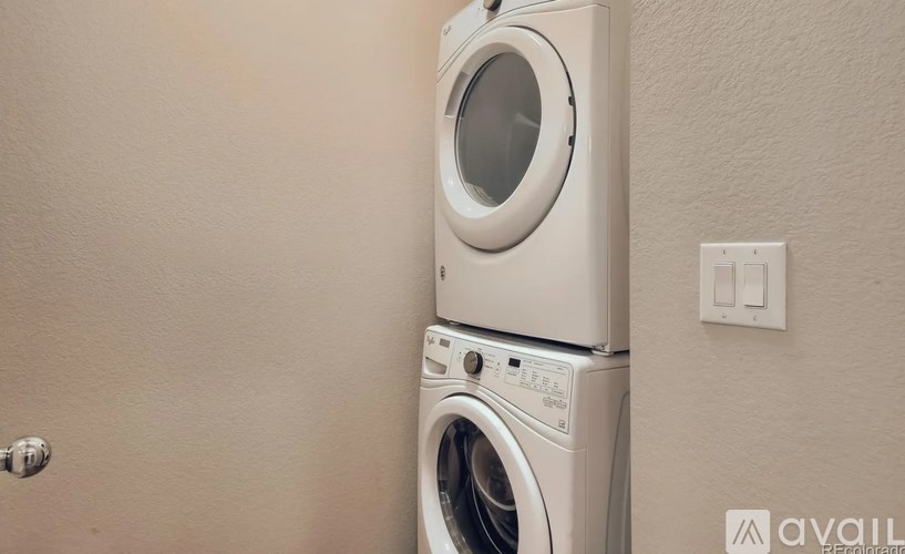 A white washing machine and dryer stacked on top of each other in a laundry room.
