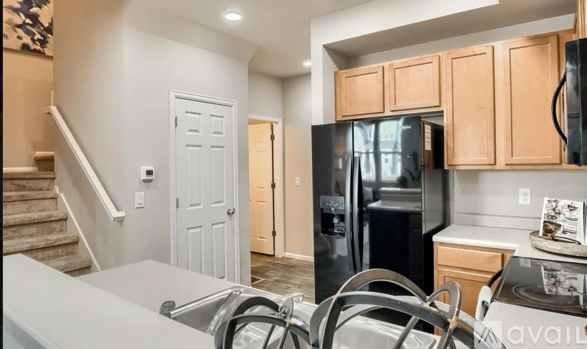 A kitchen with a black refrigerator and wooden cabinets.