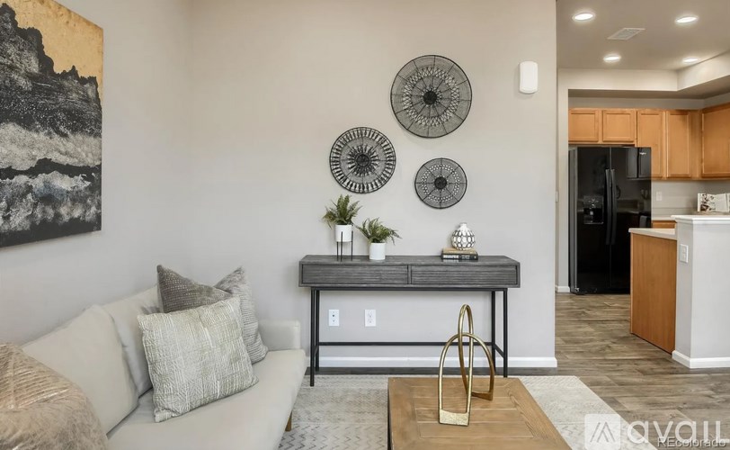 A living room with a couch, a table with a plant, and three wall decorations.