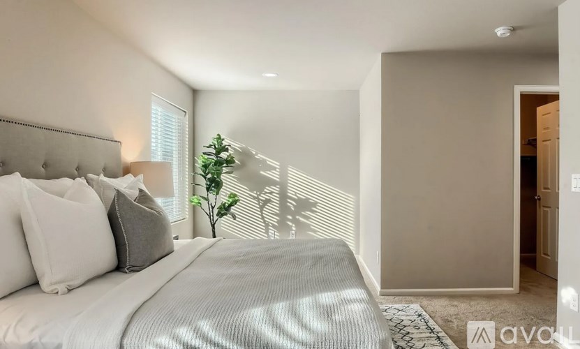 A bedroom with a large bed and a plant on the windowsill.