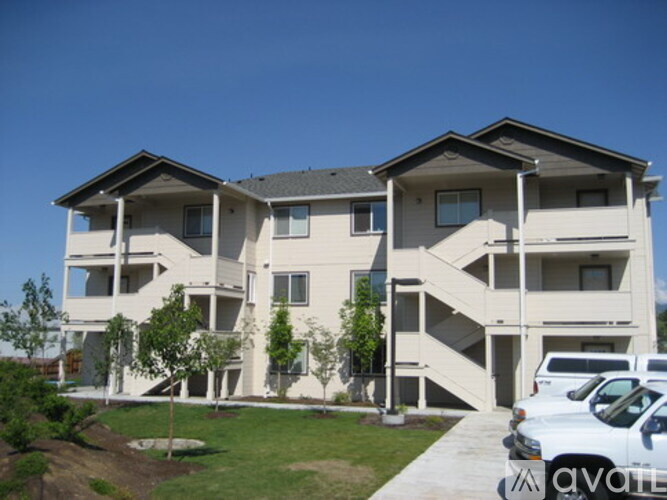A white two-story residential building with a parking lot in front.