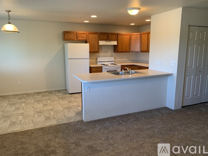 A kitchen with a white fridge and brown cabinets.