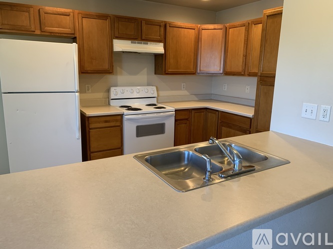 A kitchen with a white fridge, stove, and sink.