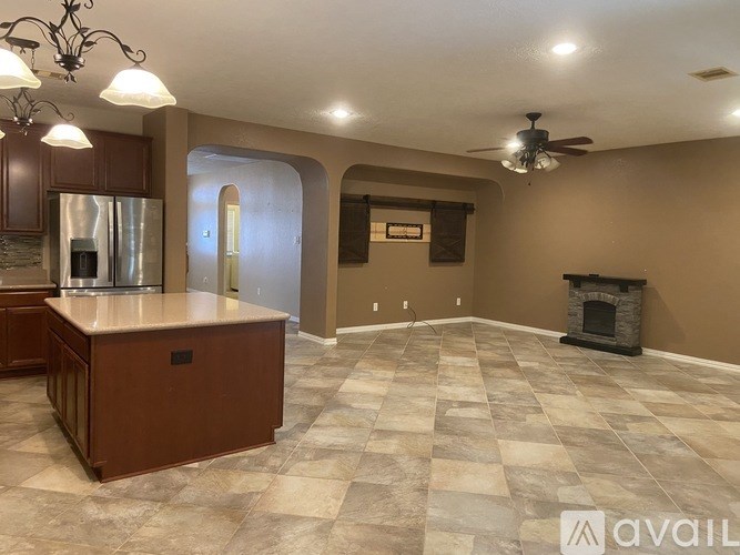 A spacious kitchen with a refrigerator, a countertop, and a fireplace in the living room.