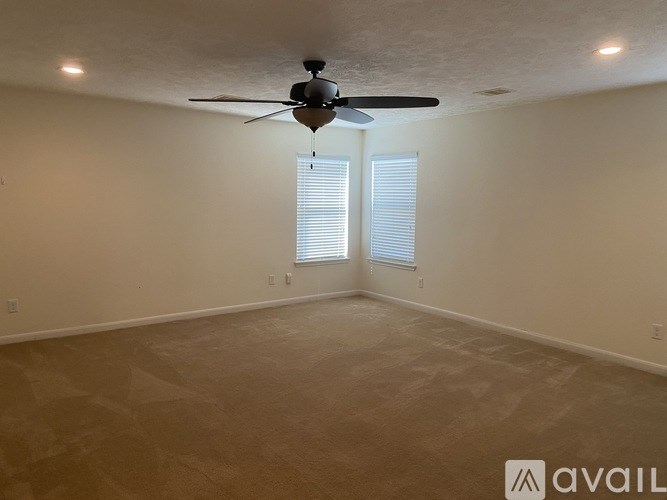 A room with a ceiling fan and two windows.