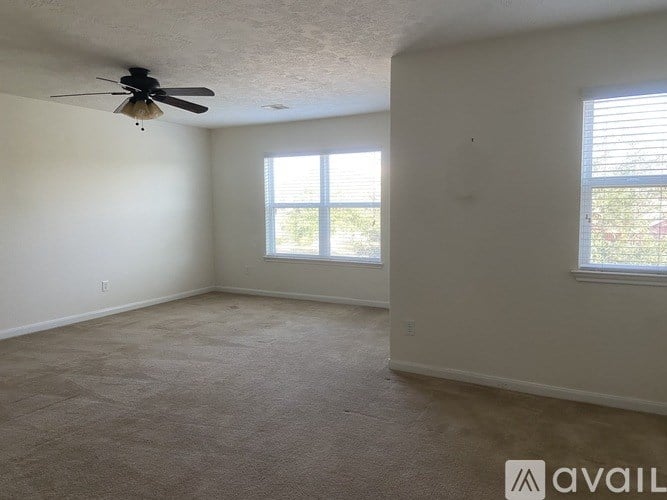 A room with a ceiling fan and two windows.