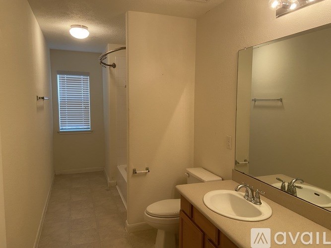 A bathroom with a toilet, sink, mirror, and shower.