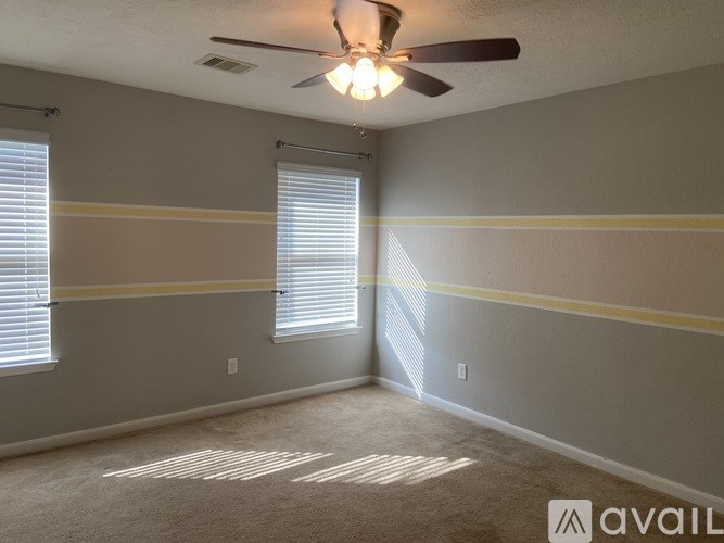 A room with a ceiling fan and a window with blinds.