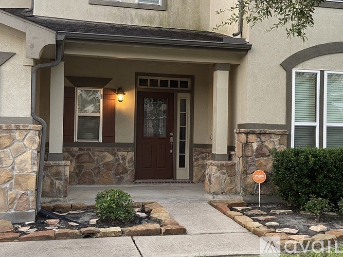 A house with a brown door and a stone pillar.