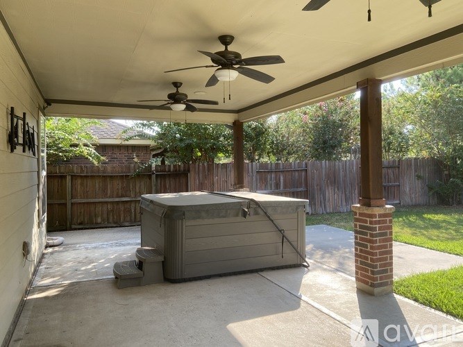A patio with a hot tub and a ceiling fan.