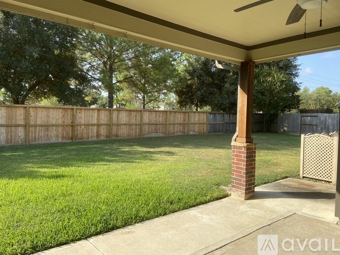 A backyard with a wooden fence and a brick pillar under a covered patio.