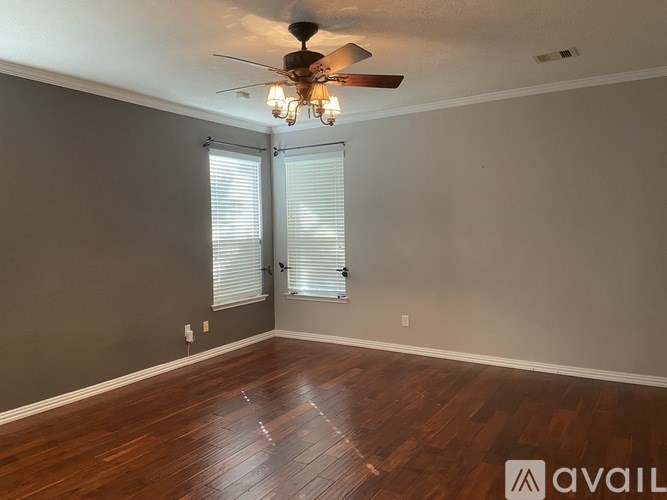 A room with a ceiling fan and wooden flooring.