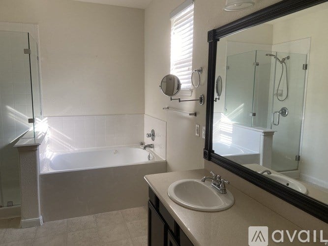 A bathroom with a tub, sink, and mirror.