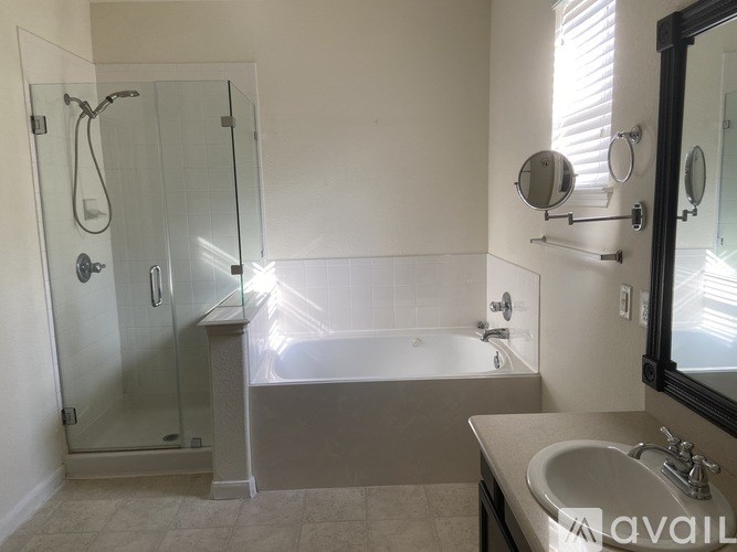 A bathroom with a glass shower door, a bathtub, a sink, and a mirror.