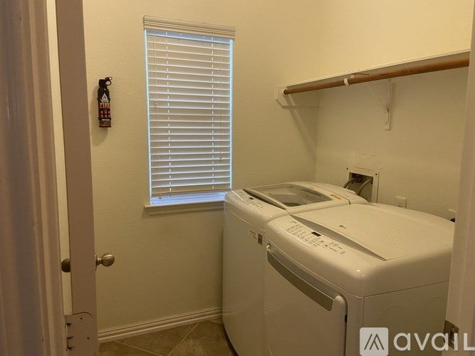 A white printer is in a small room with a window covered by blinds.