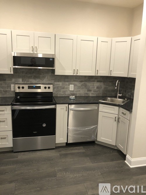 A kitchen with white cabinets and a black dishwasher.