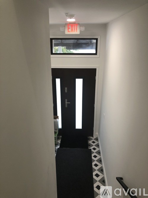 A hallway with a black and white checkered floor and a red exit sign above the door.