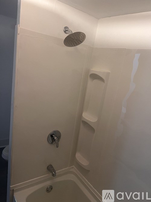 A white shower stall with a shower head and two faucets.