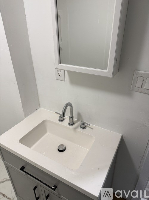 A white sink with a silver faucet and a mirror above it.