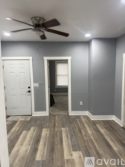 A room with a ceiling fan and a door.