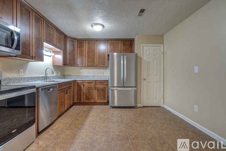 A kitchen with wooden cabinets and a stainless steel refrigerator.