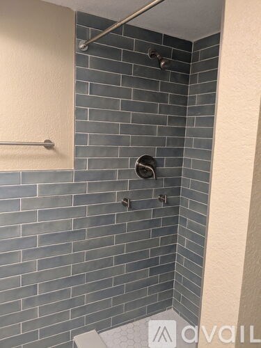 A shower area with a tile wall and a white towel bar.