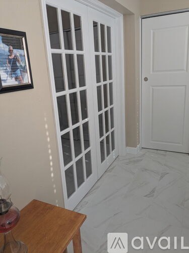 A room with a white door and a picture on the wall.