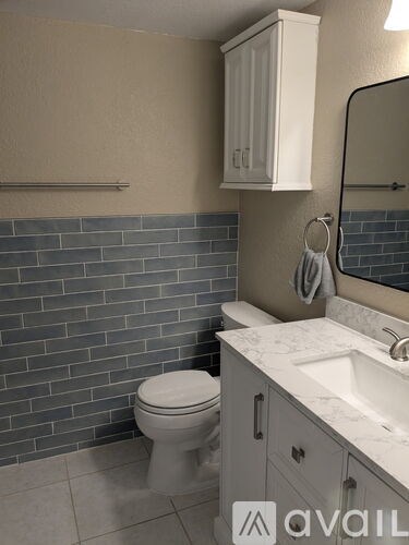 A bathroom with a toilet, sink, and mirror.