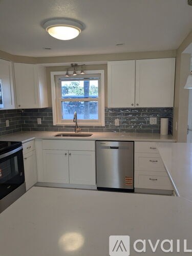 A kitchen with white cabinets and a stainless steel dishwasher.