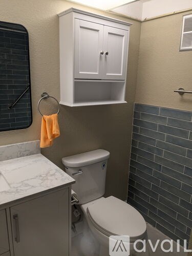 A toilet is in a bathroom with a cabinet above it.