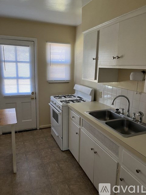 A kitchen with a stove, sink, and cabinets.
