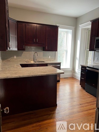 A kitchen with dark wood cabinets and a marble countertop.