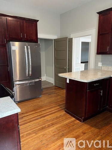 A kitchen with wooden cabinets and a stainless steel refrigerator.
